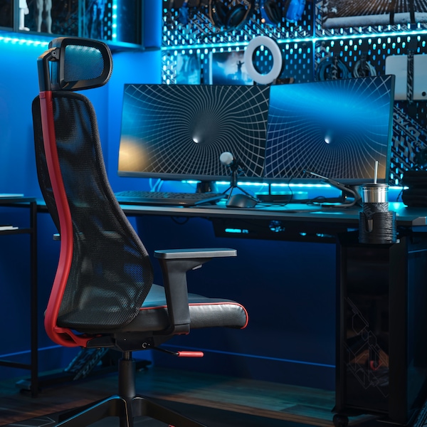 MATCHSPEL游戏椅子在书桌前拿着两个显示器。技术装备和蓝色LED灯条是在墙上。