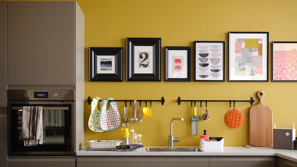 马特黑色米色厨房工作台用白色大理石效果,加上黑色的rails和黑色框架在一个黄色的照片墙。