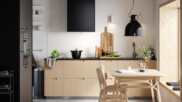 简约的厨房与光竹抽屉面板,黑色的门,竹的餐桌和两把椅子。
