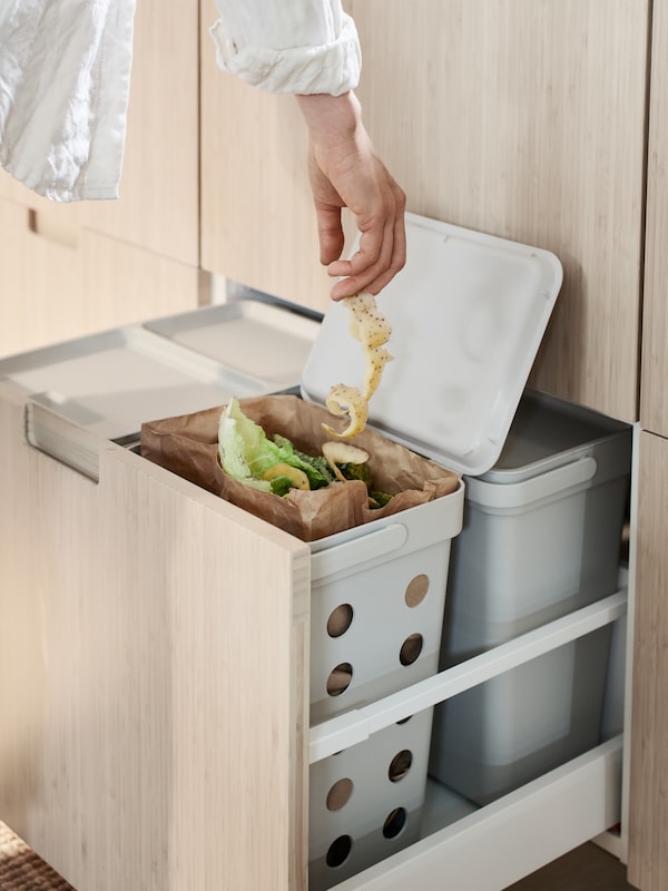 一个人处理生活垃圾的食物残渣分类装进HALLBAR废物分类垃圾箱在抽屉里有四个箱子。