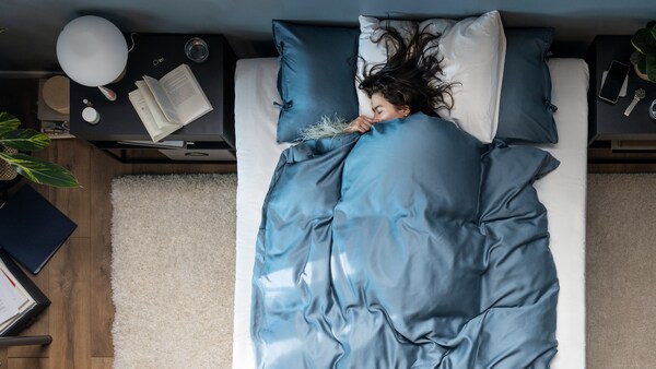 一个人躺睡在一个床上用蓝色KRITSUGA床单,站在一个白色的高桩VOLLERSLEV地毯在卧室里。
