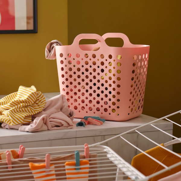 粉色SLIBB灵活的洗衣篮和一堆衣服厨房工作台,加上白色的架子上有更多的衣服。