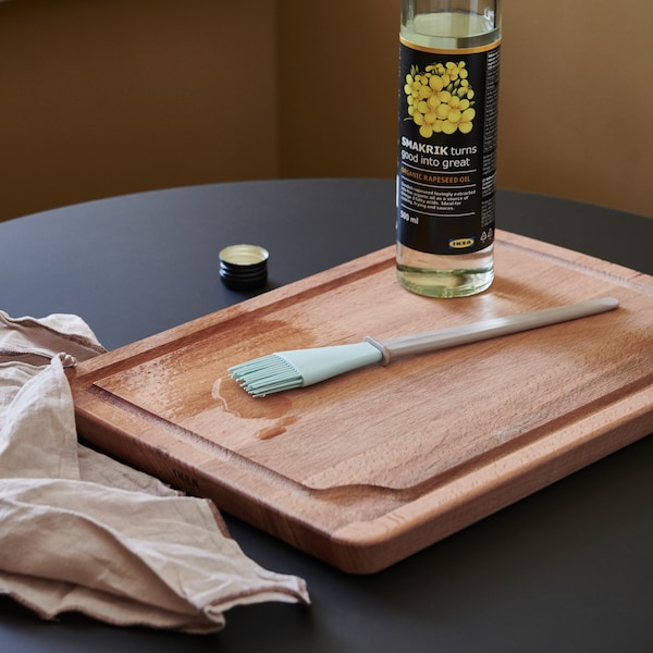 用一把小刷子PROPPMATT切菜板在海滩和一瓶菜籽油旁边桌子上的一块布。