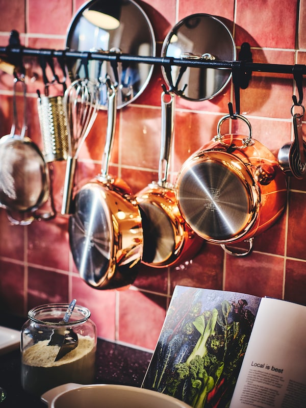 红色,厨房瓷砖墙和烹饪工具和三个铜FINMAT锅HULTARP铁路用钩子挂着盖子。