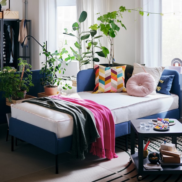 与五彩缤纷的缓冲间BLAKULLEN床的房间,一张咖啡桌,窗户和窗帘和绿色植物。