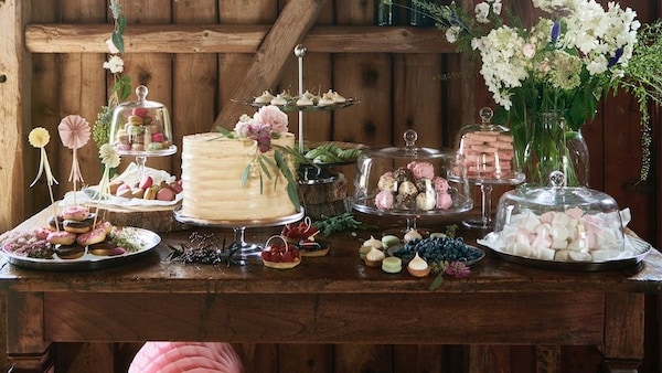 乡村环境,木桌上装饰着各式各样的蛋糕和点心和各种新鲜的绿叶。