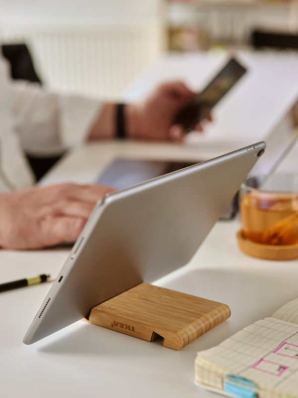银竹卑尔根夹在平板电脑上白色的书桌,前面一个人的笔记本电脑和智能手机。