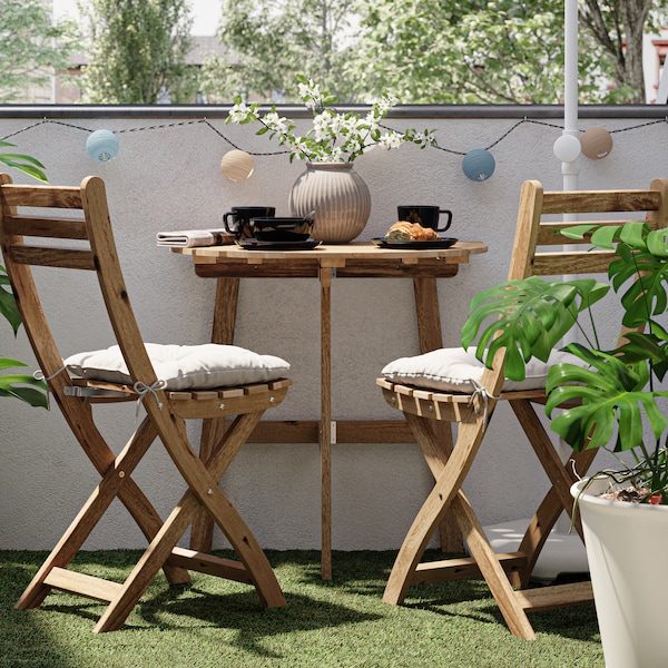 一个小阳台,一个木制的桌子和椅子,人造草装饰,蓬莱蕉在白色的盆栽植物。