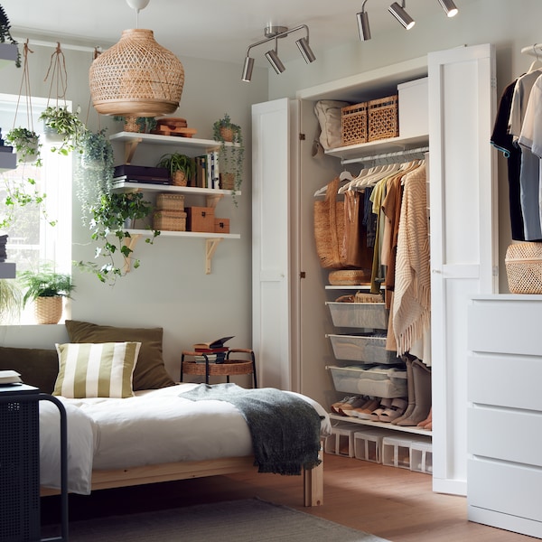 木床框架的小卧室,打开衣柜,巧妙地组织衣服,货架上盒子和植物。