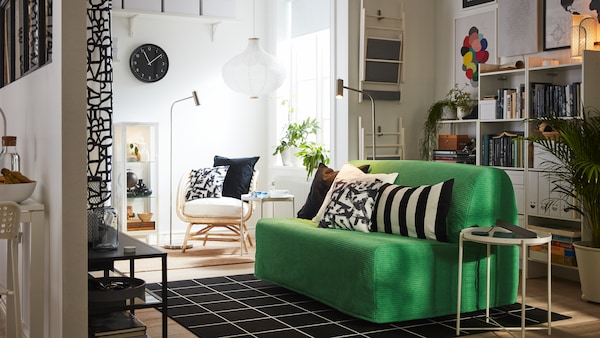 一个小工作室Vansbro亮绿色2-seat床,黑白纺织品,白色的书架,一把扶手椅。