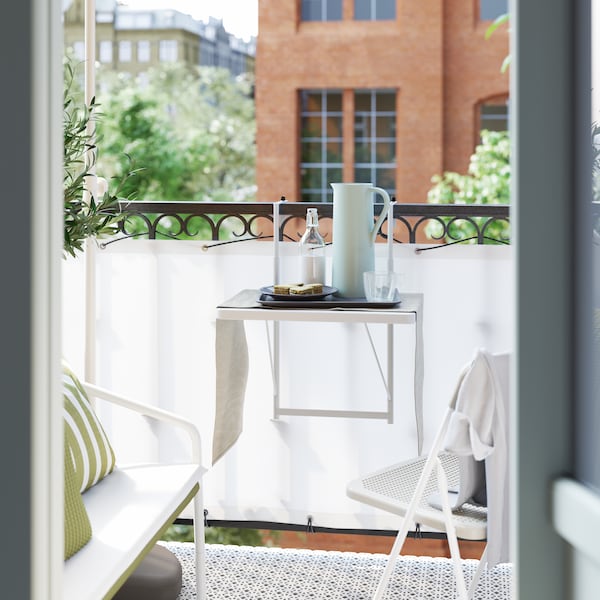一个白色的小阳台表挂在阳台栏杆,投手,一盘食物和饮料。