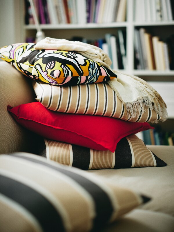 沙发,把和堆积成山的枕头与不同的靠垫套,其中两个是KORALLBUSKE与条纹靠垫套。