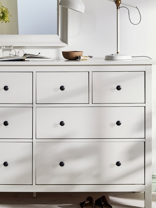灯光柔和的白色HEMNES eight-drawer衣柜和一盏灯,一碗和一副眼镜。