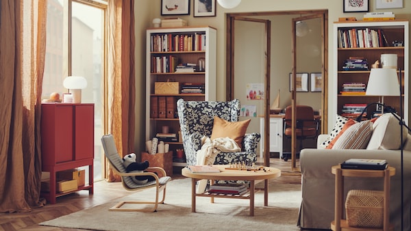 STRANDMON翼椅子是在温暖和传统风格的客厅HEMNES书柜装满书籍和物品。