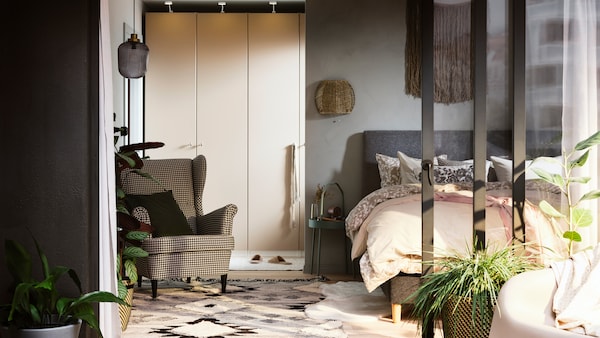 一个阳光明媚的卧室与罗马帝国由IDANAS / REINSVOLL衣柜组合床上覆盖着花和普通的床单。