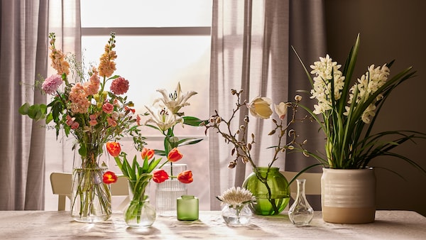 表窗口与不同的花束的绿色玻璃花瓶、透明玻璃花瓶和一个白色的陶瓷花瓶。