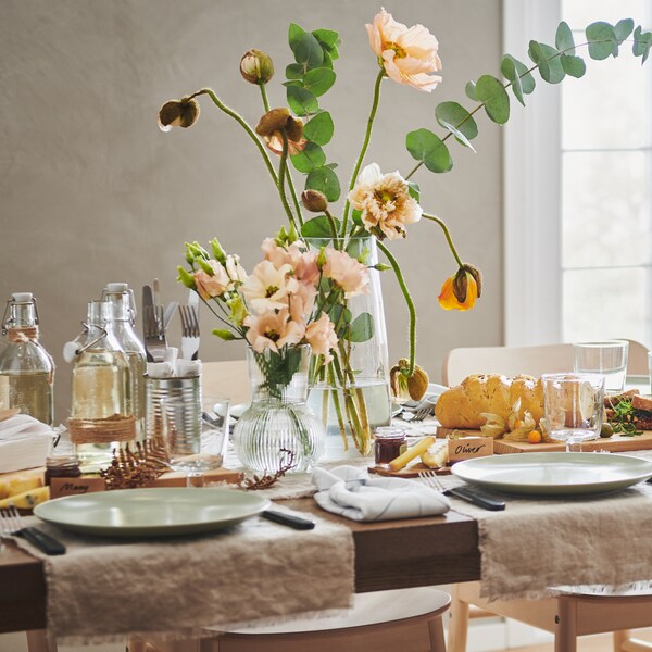 中性色调和浅绿色餐具的餐桌。桌子上有两个花瓶、食物和瓶子。