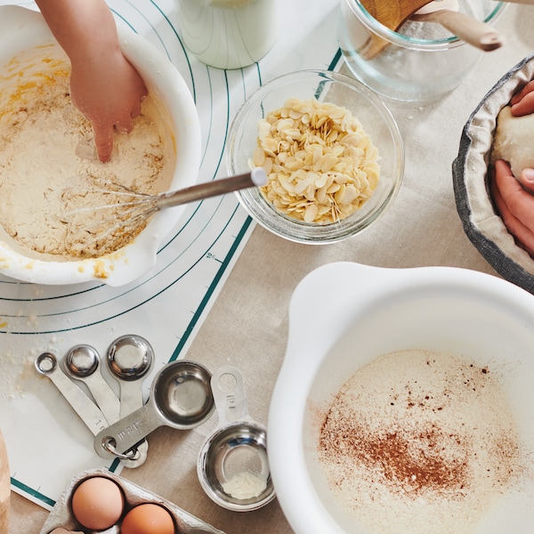 桌面mid-baking会话——鸡蛋、面粉和餐具。手在白色团工作VISPAD banneton碗和混合。