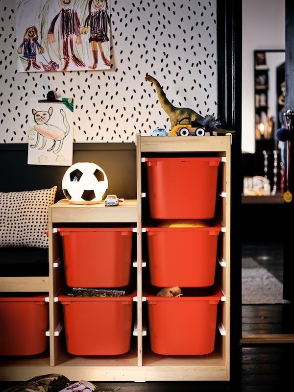 一个toy-filled TROFAST单元与橙色的存储盒在孩子的房间里设置在一个黑白色系。