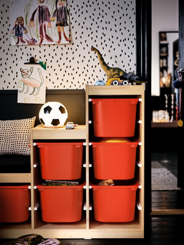 一个toy-filled TROFAST单元与橙色的存储盒在孩子的房间里设置在一个黑白色系。