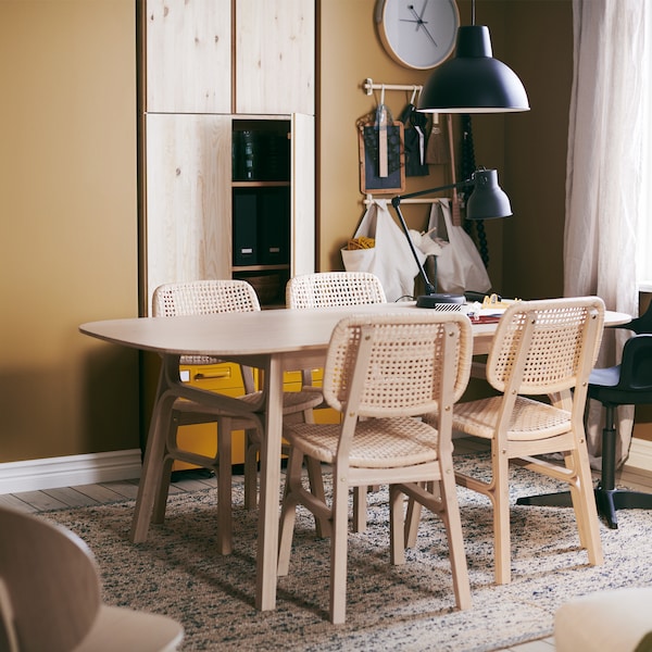 VOXLOV桌子和四把椅子,站在MELHOLT flatwoven地毯,一个ROTBLOTA墙上的挂钟挂灯。