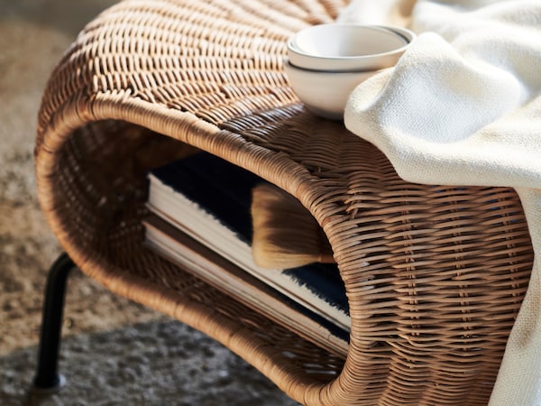 一个白色毯子和三个白色碗GAMLEHULT脚凳,里面书籍存储。