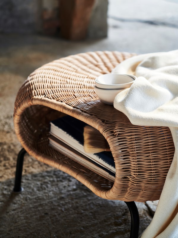 一张白色的毯子和三个白色的碗放在一个GAMLEHULT脚凳上，脚凳里放着书。