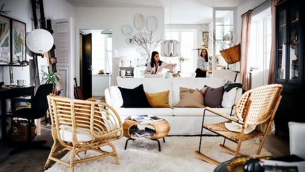 白色乡村式的生活区域和两个女人背后的白色BACKSALEN沙发前的地毯和两个扶手椅。