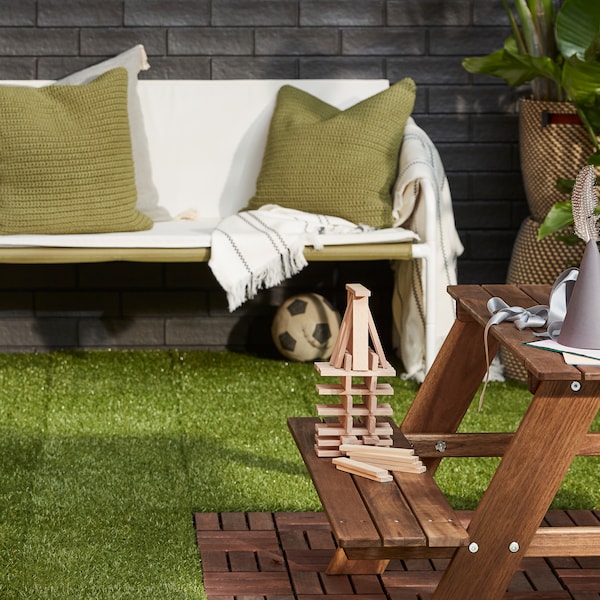 白色绿/米色沙发,一盆花和一个浅棕色的儿童人工草地上野餐桌上地板装饰。