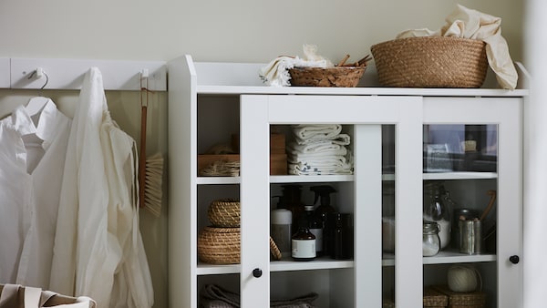 白色HAUGA玻璃门柜,一个推拉门微微张开,篮子和配件。
