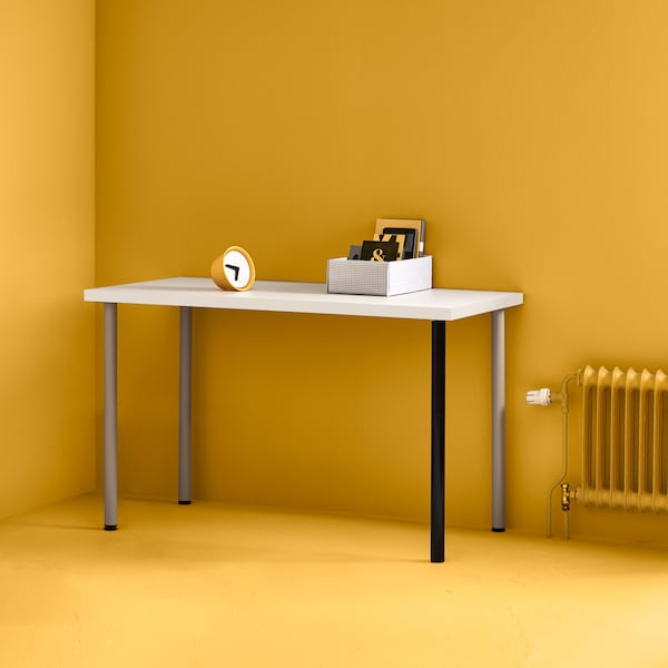 白色LINNMON桌面有银色和黑色的腿在角落里的亮黄色房间旁边还有一个黄色的散热器。