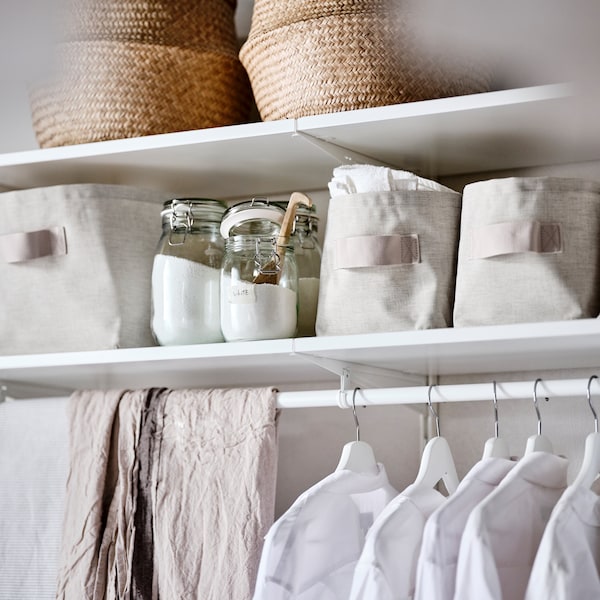 白色衣柜组合持有海草篮子,米色纺织存储篮子和白色衣服衣架。