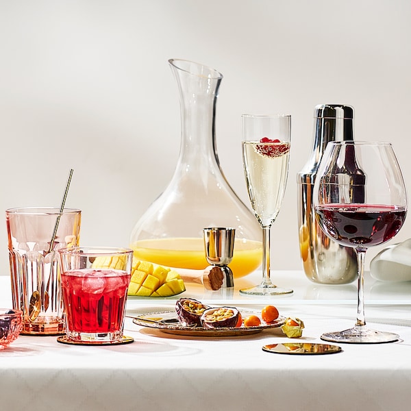 葡萄酒杯,香槟酒杯,两个酒杯和一个透明的玻璃玻璃水瓶,桌子上有白色的桌布。