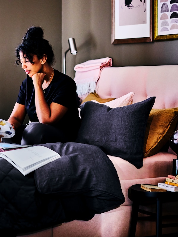 一个女人看杂志在幕后坐在在一个亮粉红色IDANAS存储床软垫。