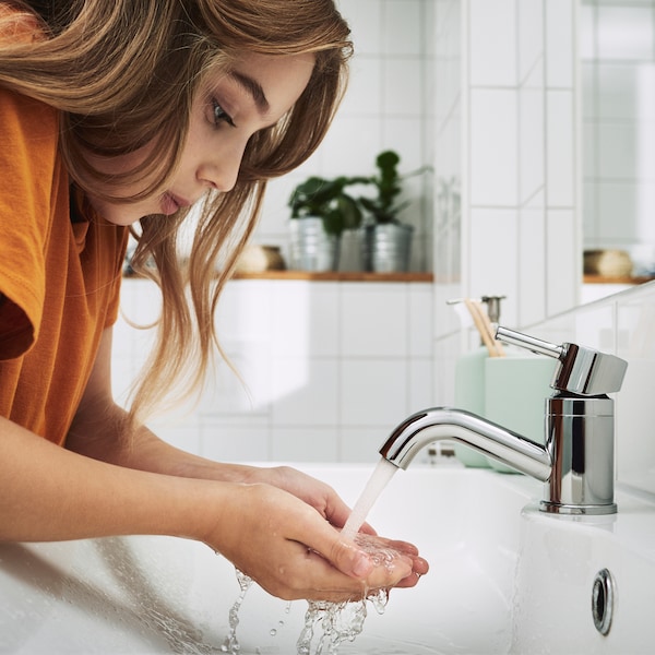 棕色长发,一个小孩站在一个白色的瓷砖浴室清洗他们的手在脸盆。