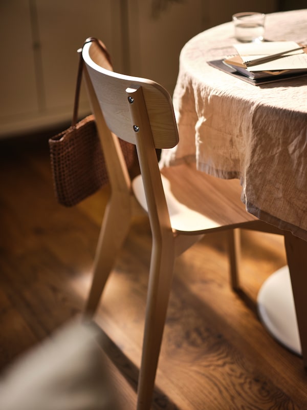 火山灰LISABO椅子的桌子上在桌布上,挂着一个手提包从后面的椅子上。