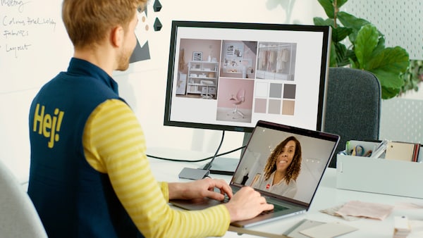 宜家的亚博平台信誉怎么样同事视频通话客户,看室内设计图片和颜色色板在另一个监视器。