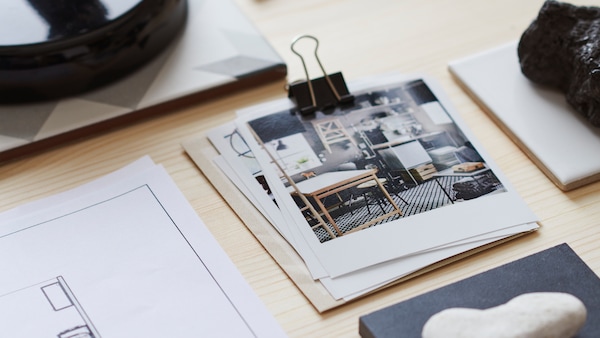 宜家的亚博平台信誉怎么样室内设计在一堆照片由一个大铁夹子,旁边的角落里草图方案,在一个木制的桌子。