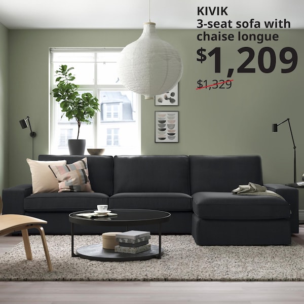 无烟煤的l型KIVIK沙发颜色是放在前面的窗户在客厅里。地毯放在沙发上,面前的黑框VITTSJO咖啡桌。文字写着:KIVIK 3三种座位沙发和躺椅,1209美元,先前的价格1329美元。