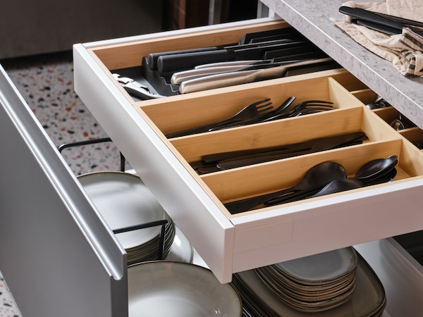 一个开放式厨房的抽屉里和盘子,另一个厨房抽屉里面有光竹UPPDATERA餐具/刀架。