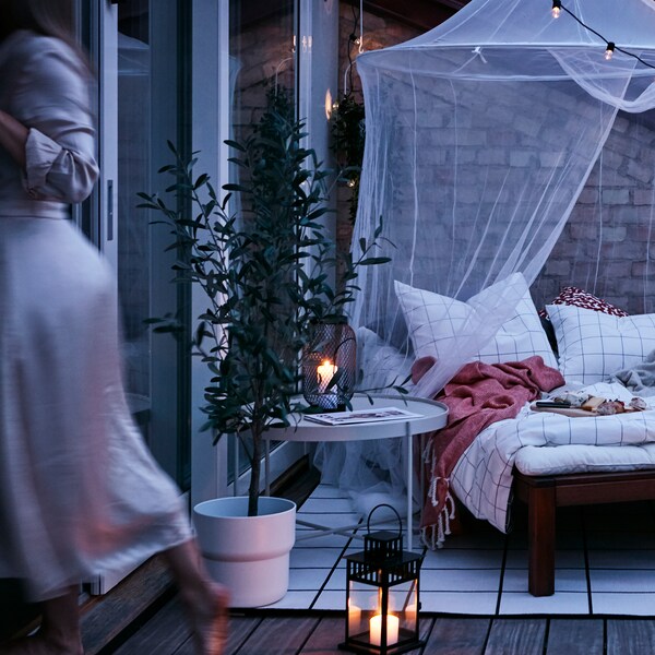 黄昏时分的室外露台，由太阳躺椅、网、地毯、灯笼和室外串线灯组成的舒适巢穴。