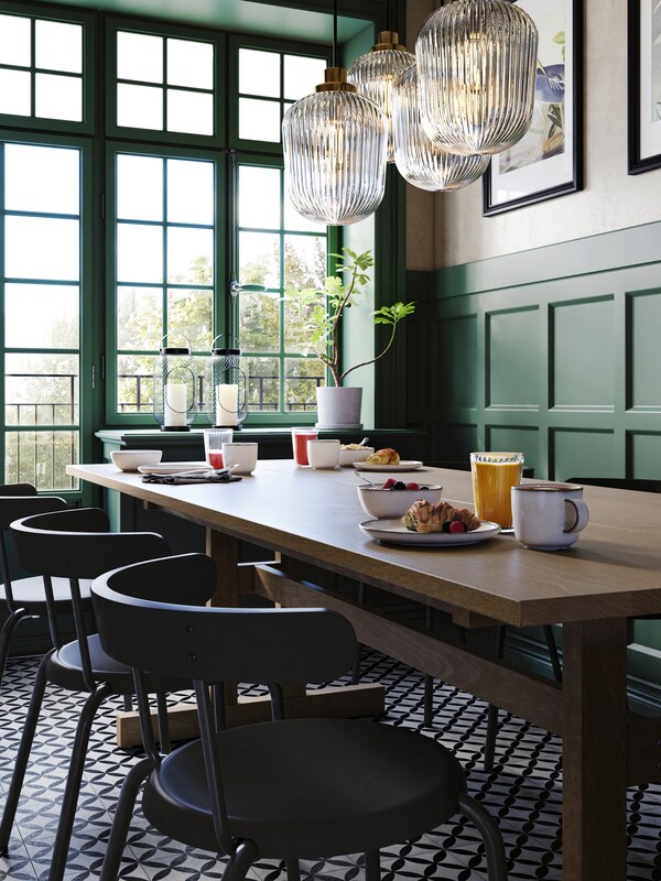 Antracytowe krzesła YNGVAR przy szaro-brązowym偷jadalnianym KLIMPFJALL w zielonym wnętrzu restauracji z dużymi oknami。