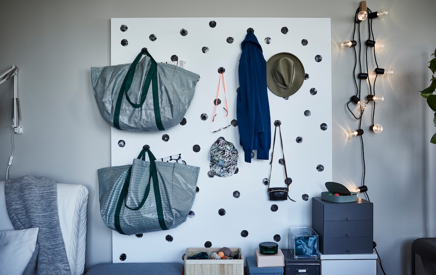 包和帽子挂在白墙存储有黑点,一张画胶合板和厨房旋钮。