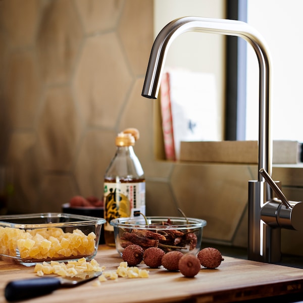 棕色的木头砧板有两个玻璃容器,下一个ALMAREN厨房冷热水混合龙头在不锈钢的颜色。