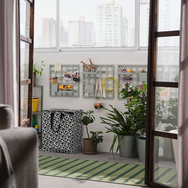 开放与灰绿色的阳台SNICKRA存储板在墙上,黑色/白色袋子,大盆栽和地毯。