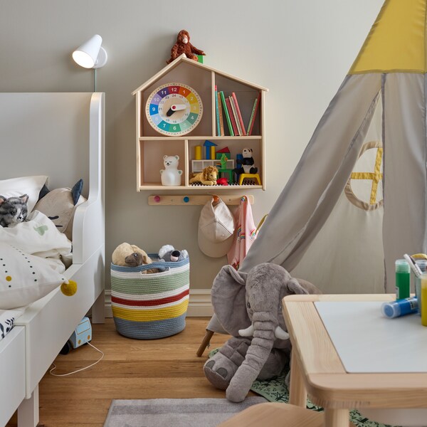 静脉ausziehbares BUSUNGE Bettgestell在Weißsteht neben einem Spielzelt和einem Kindertisch。一个der魔杖hangt静脉Puppenhaus / Wandregal。
