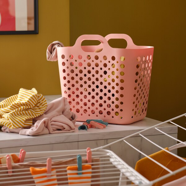 在粉色SLIBB fleksibel vasketøjskurv og En stak tøj pa等køkkenbord og et hvidt tørrestativ地中海tøj。