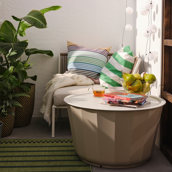 Et米色LAGASKAR sofabord pa等grøn——og lillastribet tæppe ved en hvid /米色hjørnesektion og tæppe。