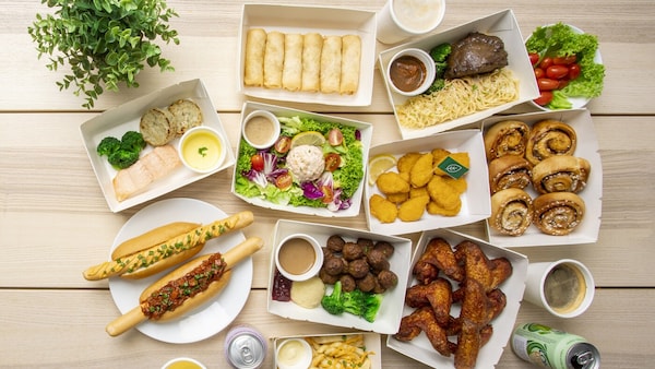 亚博平台信誉怎么样宜家食品外卖包放在桌子上——包括肉丸,热狗,鸡翅,薯条、鲑鱼、春卷、肉桂卷,沙拉,和饮料。