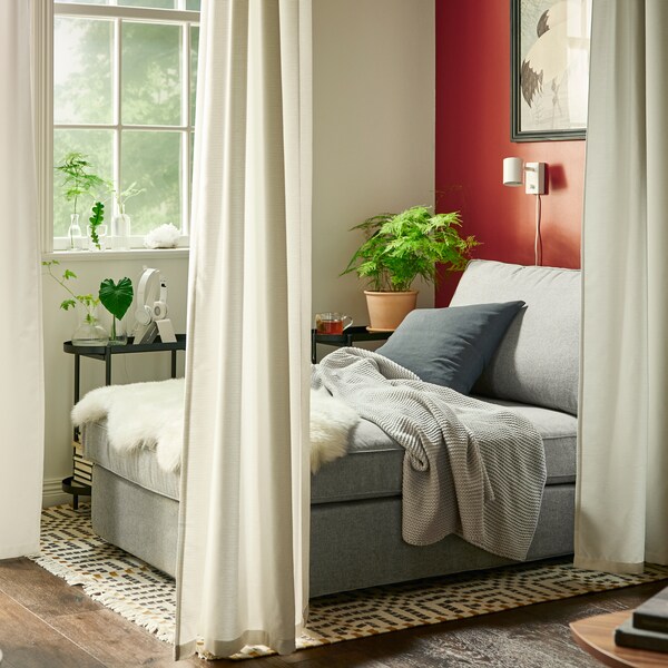 在房间的一个角落里是一个米灰色KIVIK躺椅GUNNLAUG窗帘挂在角落里。